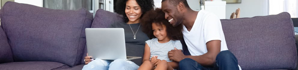 Family sitting on couch looking at laptop