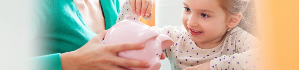 Child putting money in a piggy bank